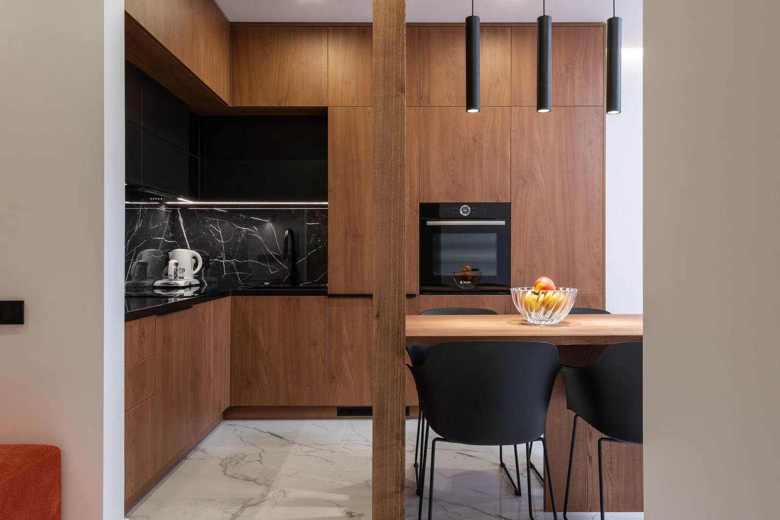 Walnut slab cabinetry with a black marble splashback